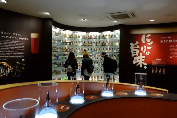 Wall display of hundreds of sake bottles above the tasting counter at Kizakura Fushimi Sake Brewery and Museum, Kyoto