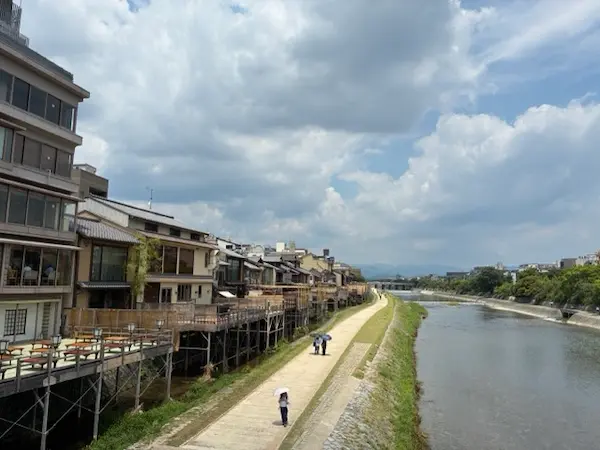 Visitors walking along the Kamo River promenade past traditional riverside restaurants