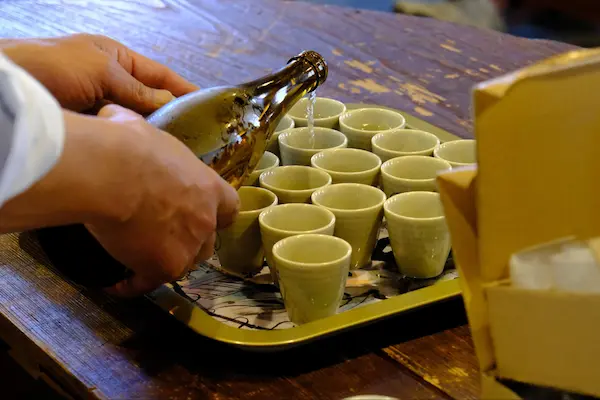 Sake being poured into tasting cups for U.S. university students at Matsumoto Sake Brewery
