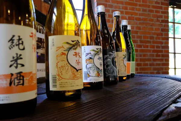 Momo no Shizuku and other Matsumoto Sake Brewery junmai sake bottles displayed on a wooden counter in Fushimi, Kyoto