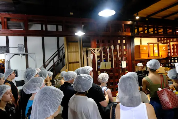 U.S. university students listening to a brewery staff explanation inside a traditional kura at Matsumoto Sake Brewery in Fushimi